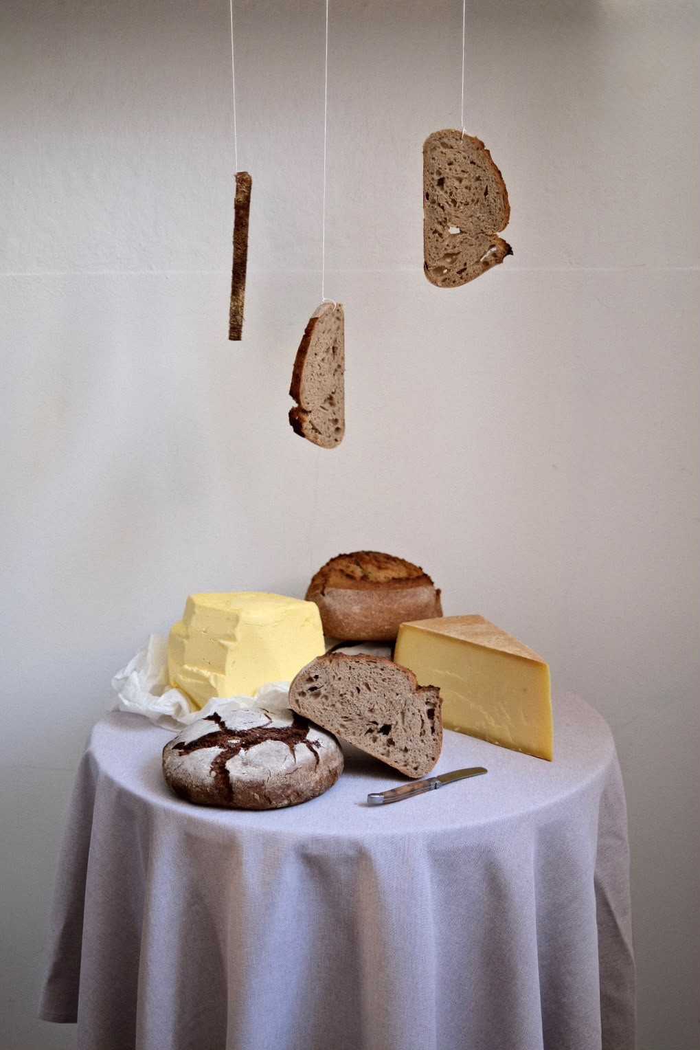 Schwebende Brotscheiben über Butter, Käse und Laiben